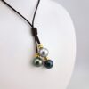 Collier 'grappe' en cuir marron, intercalaires en plaqué or, fermoir nacre, 3 perles de Tahiti rondes, catégorie C 11.2mm vert foncé / 11.1mm gris souris / 10.8mm peacock